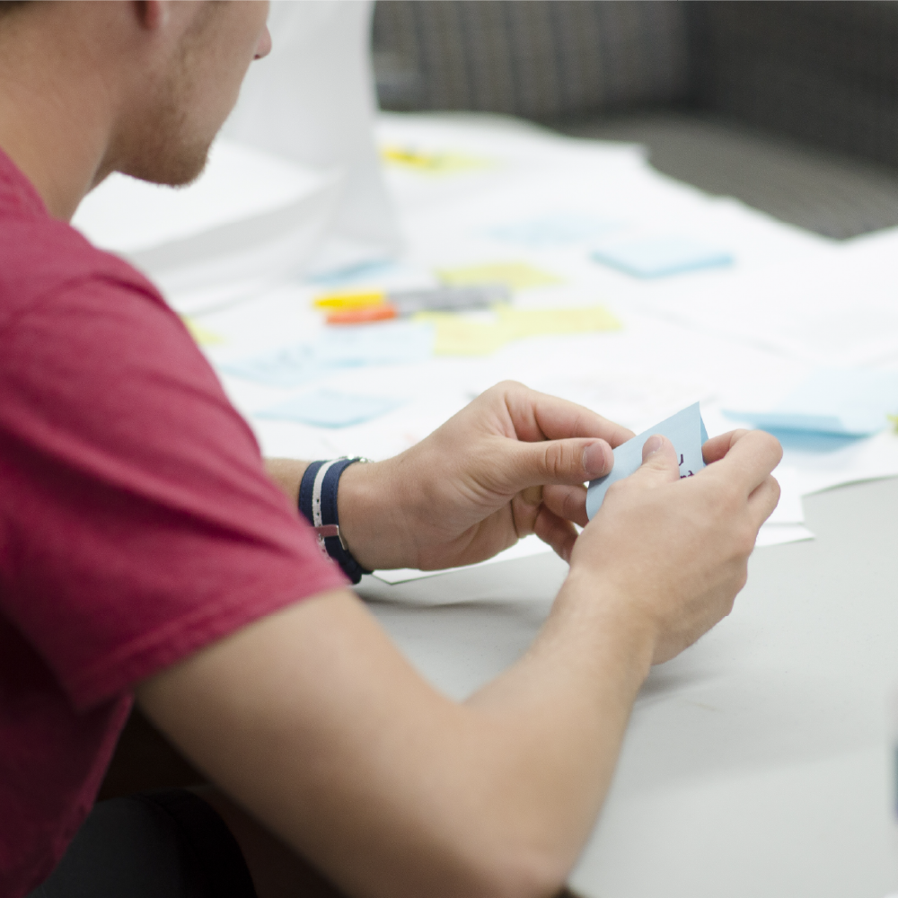 Osoba podczas pracy nad wspólnym projektem – notatki i karteczki na stole