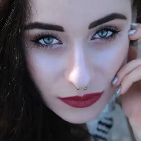 Zdjęcie kobiety w okularach przeciwsłonecznych, z kwiatem we włosach, uśmiechnięta na tle zieleni. Aleksandra Szewc – psycholożka i trenerka