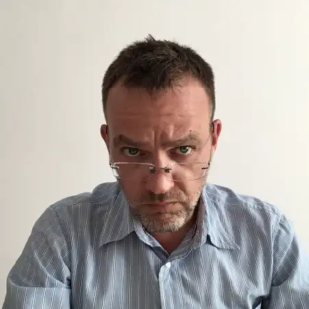 Mężczyzna w okularach, ubrany w jasną koszulę, patrzący prosto w obiektyw – Marek Jaros, psycholog i psychoterapeuta